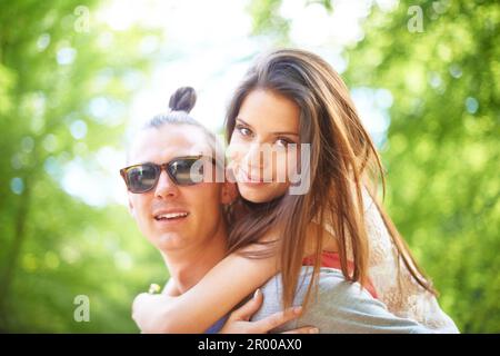 Junge Liebe. Ein trendiger junger Mann, der seiner Freundin eine Huckepack-Fahrt gibt. Stockfoto