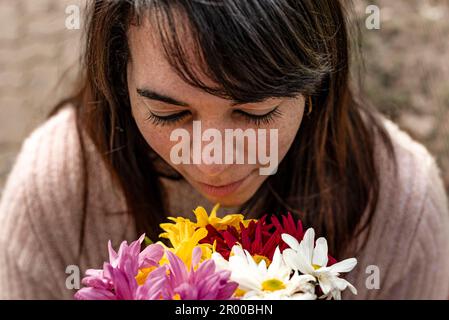 Aus dem Blickwinkel einer jungen Frau, die einen Strauß Gänseblümchen in ihren Händen riecht. Nahaufnahme. Stockfoto