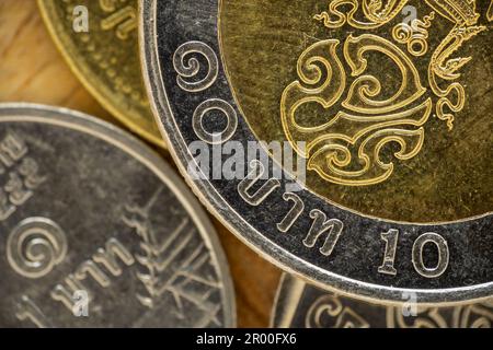 Eine Gruppe thailändischer Münzen mit einer Münze von zehn Baht. Makro, Nahaufnahme Stockfoto