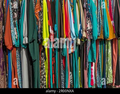 Ich habe auf einem Flohmarkt bunte Kleidung an einem Regal getragen Stockfoto