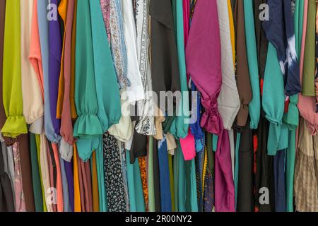 Ich habe auf einem Flohmarkt bunte Kleidung an einem Regal getragen Stockfoto
