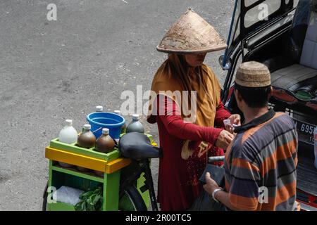 Kräutermedikamentenverkäufer und ihre Käufer. JAMU ist ein traditionelles Getränk in Indonesien, das aus verschiedenen Gewürzen und Pflanzen hergestellt wird. Stockfoto