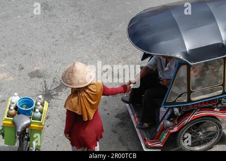 Kräutermedikamentenverkäufer und ihre Käufer. JAMU ist ein traditionelles Getränk in Indonesien, das aus verschiedenen Gewürzen und Pflanzen hergestellt wird. Stockfoto