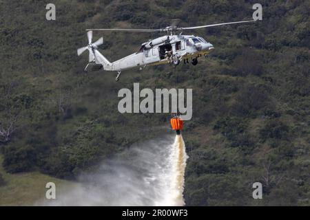 Camp Pendleton, Kalifornien, USA. 19. April 2023. EIN US-AMERIKANISCHER Navy SH-60 Sea Hawk Hubschrauber lässt Wasser aus einem bambi-Eimer über einem Zielgebiet fallen während der jährlichen Feuerwehrübung von Cory Iverson Wildland am Las Pulgas Lake im Marine Corps Base Camp Pendleton, Kalifornien, 19. April 2023. Bei der jährlich stattfindenden Feuerwehrübung von Cory Iverson Wildland geht es um die behördenübergreifende Zusammenarbeit zwischen dem California Department of Forestry and Fire Protection, dem San Diego County Sheriff's Department und dem Department of Defense. Während der Übung arbeitet jede Einheit zusammen, um eine effektive zu schaffen Stockfoto