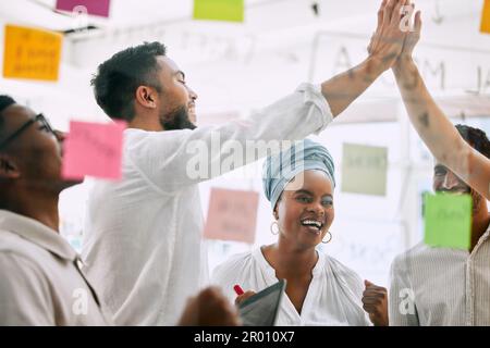 Ich habe erfolgreich einen Plan entwickelt. Eine Gruppe junger Geschäftsleute, die sich gegenseitig in einem Büro einen High Five geben. Stockfoto