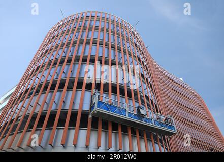 Arbeiter am Gerüstaufzug, der die Wandfassade des neuen Gebäudes isoliert. Stockfoto