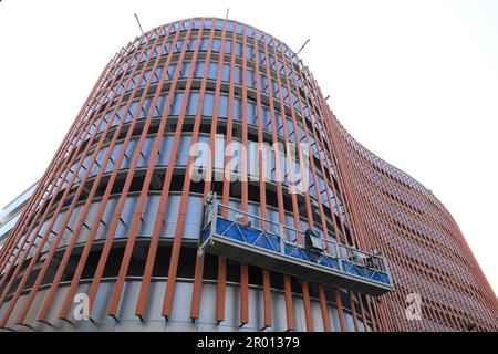 Arbeiter am Gerüstaufzug, der die Wandfassade des neuen Gebäudes isoliert. Stockfoto