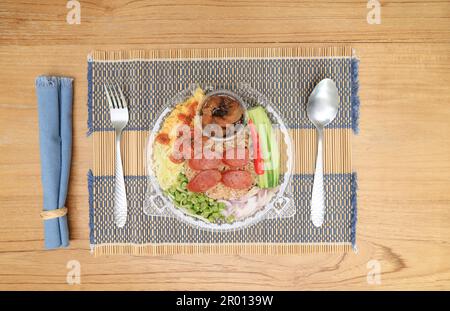 Gebratener Reis mit Thai-Garnelen und süßem Schweinefleisch und verschiedenen Gewürzen auf einem Holztisch. Stockfoto