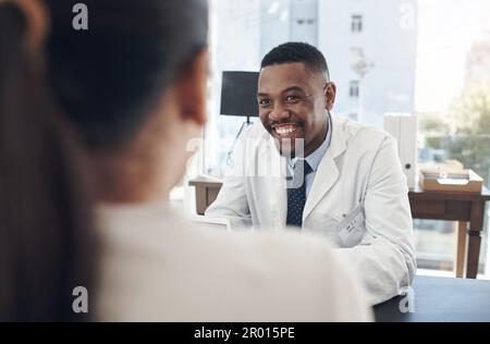 Ein Lächeln kann jeden Tag erhellen. Ein junger Arzt, der mit einem Patienten in einer Praxis spricht. Stockfoto