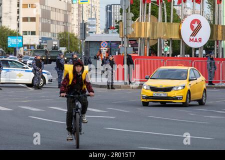 Moskau, Russland. 4. Mai 2023. Ein Taxiwagen und Kuriere des Yandex-Lieferservice fahren auf dem Taganskaya-Platz entlang der Passage der Militärfahrzeuge zum Roten Platz, um eine Nachtprobe für die Siegesparade in Moskau, Russland, zu besuchen. Die Parade findet am 9. Mai auf dem Roten Platz in Moskau statt, um 78 Jahre des Sieges im Zweiten Weltkrieg zu feiern. Stockfoto