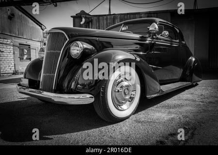 Ein sehr alter Caddilac in Originalzustand steht vor einer Garage Stockfoto