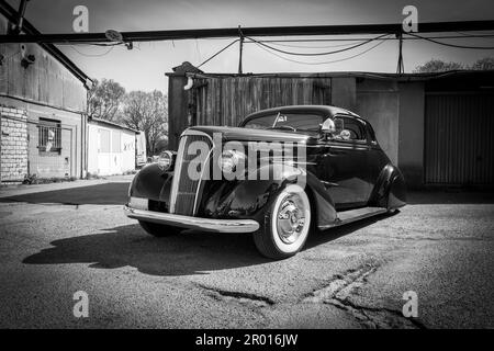 Ein sehr alter Caddilac in Originalzustand steht vor einer Garage Stockfoto