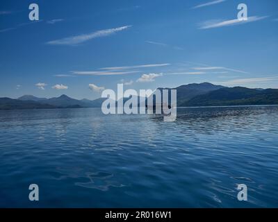 Bootsfahrt über einen tiefen blauen See im schottischen Hochland an einem sonnigen Tag. Stockfoto
