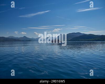 Bootsfahrt über einen tiefen blauen See im schottischen Hochland an einem sonnigen Tag. Stockfoto
