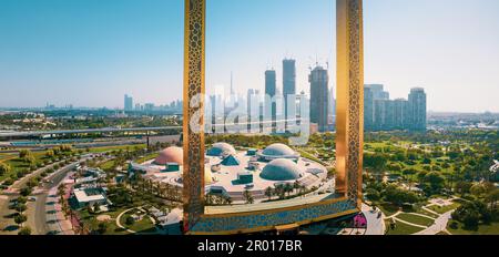 Dubai Skyline durch den großen goldenen Rahmen mit nahe gelegenem Park und Dubai Skyline aus der Vogelperspektive auf das Emirat Stockfoto