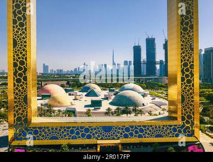 Dubai Skyline durch den großen goldenen Rahmen mit nahe gelegenem Park und Dubai Skyline aus der Vogelperspektive auf das Emirat Stockfoto