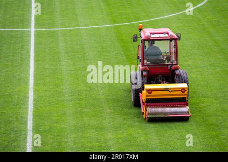Ein Mann in einem Traktor mit einer Scheibenbohrmaschine sät Gras auf dem Fußballfeld Stockfoto