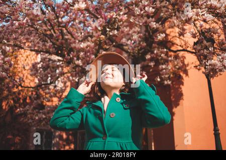Frau läuft durch Prag, genießt Sonne und gutes Wetter, steht unter einem wunderschönen Magnolienbaum. hut Stockfoto