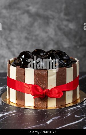 Kuchen mit Profiteroles und Schokoladencreme. Geburtstagskuchen oder Festtagskuchen. Kuchen mit Profiteroles und dunkler Schokoladencreme auf dunklem Hintergrund. Schließen Stockfoto