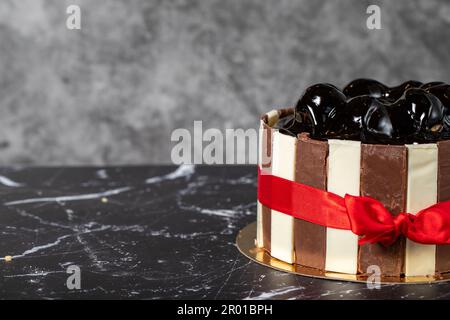 Kuchen mit Profiteroles und Schokoladencreme. Geburtstagskuchen oder Festtagskuchen. Kuchen mit Profiteroles und dunkler Schokoladencreme auf dunklem Hintergrund. Kopieren en Stockfoto