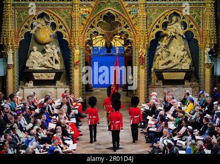 Soldaten gehen an Gästen vorbei, die in Westminster Abbey, London, vor der Krönung von König Karl III. Und Königin Camilla sitzen. Foto: Samstag, 6. Mai 2023. Stockfoto
