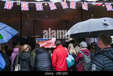 Brighton UK, 6. Mai 2023 - die Massen beobachten heute im Regen die Krönung von König Charles III auf einer großen Leinwand in Brightons Jubilee Square : Credit Simon Dack / Alamy Live News Stockfoto