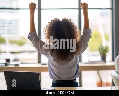 Glückliche junge Studentin oder Mitarbeiterin, die mit einem Laptop ein erfolgreiches Ziel erreicht hat und online gute neue Produkte erhält Stockfoto