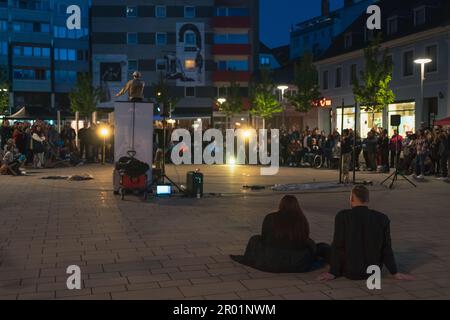 Kaiserslautern, Deutschland. 5. Mai 2023. Leute, die auf dem Boden sitzen und die Funky Monkeys Street Art Aufführung am Schillerplatz genießen. Das Street Art Festival findet in der Innenstadt über einen Zeitraum von drei Tagen statt. Die Stadt Kaiserslautern lud internationale Künstler aus 14 Nationen ein. Kredit: Gustav Zygmund/Alamy News Stockfoto