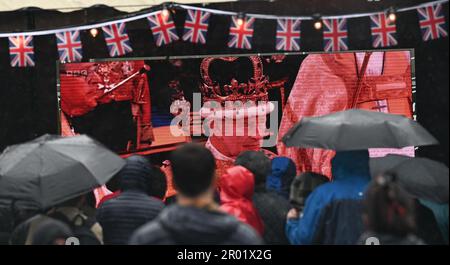 Brighton UK, 6. Mai 2023 - die Massen beobachten heute im Regen die Krönung von König Charles III auf einer großen Leinwand in Brightons Jubilee Square : Credit Simon Dack / Alamy Live News Stockfoto