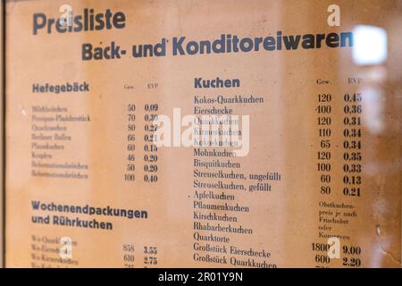 06. Mai 2023, Brandenburg, Lübbenau: Hinter Glas hängt eine Preisliste für Backwaren und Süßwaren. Essen wird in der DDR subventioniert und ist sehr günstig. Die Ausstellung, die bis Februar 2024 im Lübbenau Spreewald Museum zu sehen ist, befasst sich mit dem „Einkaufen in der DDR“ zwischen Planwirtschaft und Tauschen. Fotografien, Originalverpackungen und Erfahrungsberichte zeigen, was wann zu einer knappen Ware wurde. Foto: Frank Hammerschmidt/dpa Stockfoto