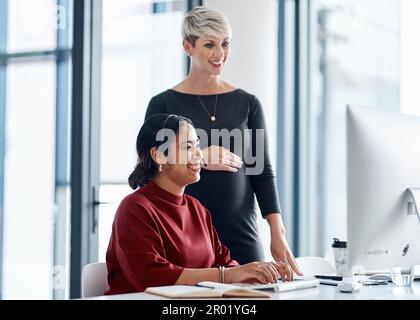 Immer da, um einander zu helfen. Eine Geschäftsfrau, die einem Kollegen in einem Callcenter hilft. Stockfoto