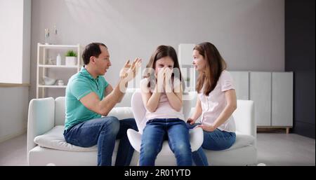 Eltern sitzen auf dem Sofa streiten Lautstark hinter Mädchen für Ihre Ohren Stockfoto