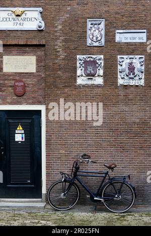 Alte Giebel an einer Wand, die Handwerke und Berufe der Hausbewohner mit Fahrrädern in Amsterdam, Holland, Niederlande, zeigen. Stockfoto