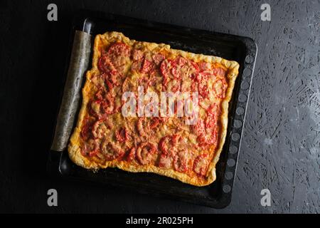 Pizza mit Tomaten, Wurst und Käse in Backform Stockfoto