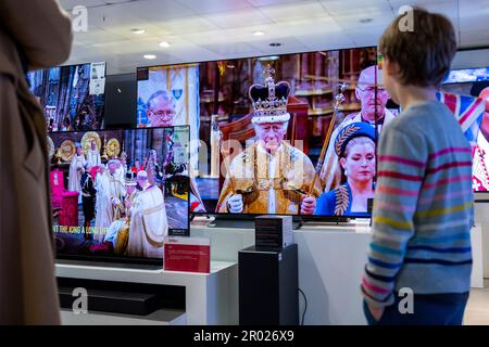 London, Großbritannien. 6. Mai 2023 Grayson, 5 Jahre alt, beobachtet gemeinsam mit anderen die Krönung von König Charles III. Und Königin Camilla auf Großbildfernsehern im Flagship John Lewis Kaufhaus in der Oxford Street. Dies ist die erste Krönung des Vereinigten Königreichs seit 70 Jahren und die erste im digitalen Zeitalter. Kredit: Stephen Chung / Alamy Live News Stockfoto