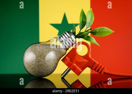 Stöpsel, Pflanze wächst in der Glühbirne und Senegal-Flagge. Konzept für umweltfreundliche erneuerbare Energien. Stockfoto