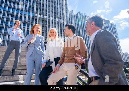 In einem entspannten Moment in der Halbzeit zu sprechen. Gruppe von Kollegen im Freien in einem Firmenbüro Stockfoto