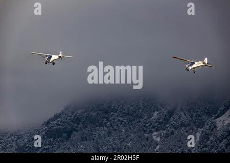 Zwei Hochflügelflugzeuge im Formationsflug, Schnee liegt auf den Bergen, Wolken, Flughafen Kranebitten, Innsbruck, Tirol, Österreich Stockfoto