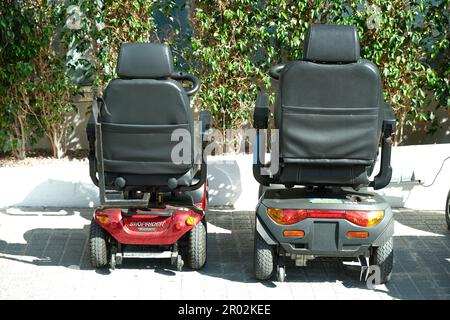 Benidorm, Spanien - 01. Mai 2023: Elektrische Roller mit vier Rädern laden auf. Personentransport für Senioren oder Menschen mit Behinderung Stockfoto