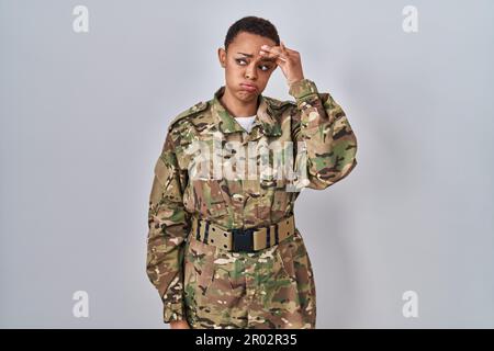 Wunderschöne afroamerikanische Frau in Tarnuniform, besorgt und gestresst über ein Problem mit der Hand auf der Stirn, nervös und ängstlich für C. Stockfoto