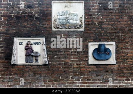 Alte Giebel an einer Wand, die Handwerke und Berufe von Hausbewohnern in Amsterdam, Holland, Niederlande zeigen. Stockfoto