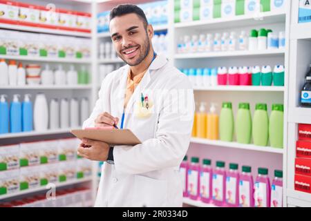 Junger hispanischer Apotheker, der auf einem Dokument in der Apotheke schreibt Stockfoto