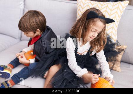 Ein süßer Junge und ein süßes Mädchen, die zu Hause eine halloween-Party feiern und Kürbis malen Stockfoto