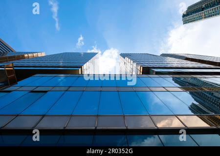 Niedriger Winkel mit Blick auf die reflektierende blaue Glasfassade. Modernes Wolkenkratzer-Bürogebäude mit blauem Himmel im Economy Financial Business District Stockfoto