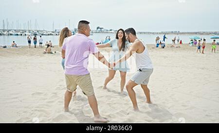 Gruppe von Menschen, die selbstbewusst lächeln, tanzen mit den Händen zusammen am Strand Stockfoto