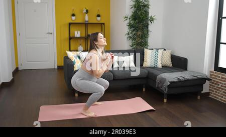 Junge schwangere, lächelnde, selbstbewusste Beinübung zu Hause Stockfoto