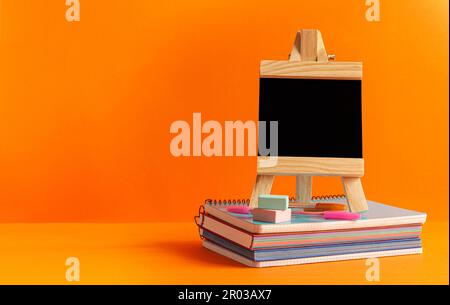 Notwendige Vorräte für eine gute Rückkehr zur Schule, zum Institut. Sie ist auf orangefarbenem Hintergrund dargestellt. Stockfoto