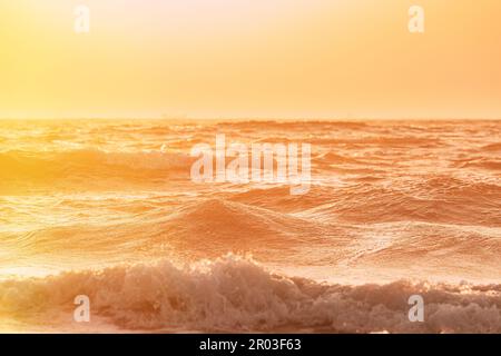 Abenduntergang über dem Meer. Riplpe Meerwasseroberfläche mit kleinen Wellen. Wasserschaum spritzt. Wunderschöne Natur mit Meereslandschaft Stockfoto