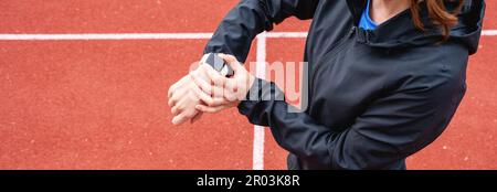 Sportlerin, die beim Workout ihre digitale Armbanduhr verwendet. Stockfoto