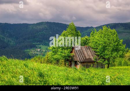 Berglandschaft im Frühling. Blick auf die Holzhütte auf der Lichtung inmitten der Bäume, Beskiden, Polen. Stockfoto